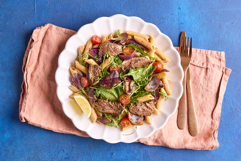 Torn between steak night and pasta night? No worries – you can have it all! Strips of tasty bavette steak are dressed in a zingy lemon, tamari and balsamic-style dressing, mixed with baby tomatoes and rocket, and served on garlicky, herby pasta.