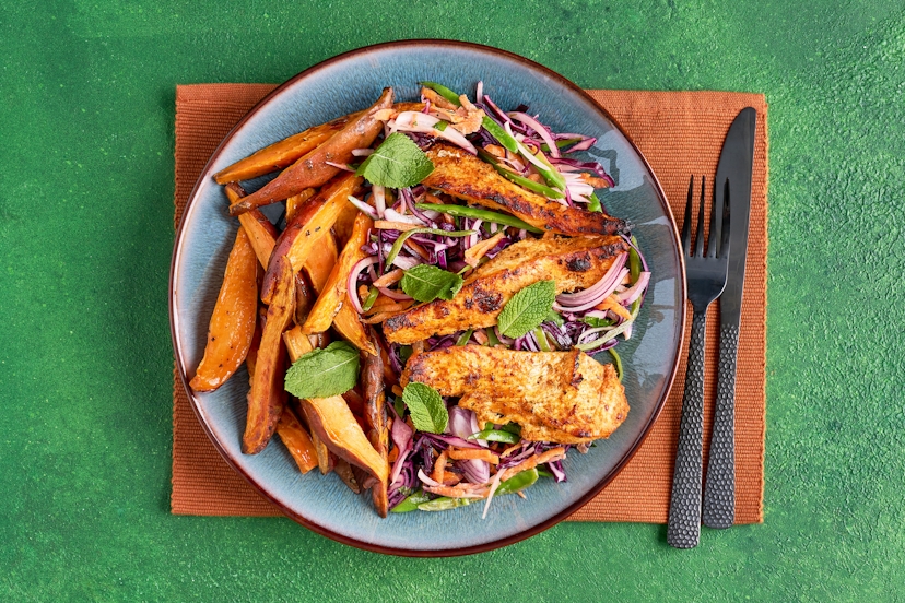 This is a feast for the eyes as well as the taste buds! Tender strips of chicken breast, marinated in Thai red curry paste, are served with golden sweet potato wedges and a crunchy cabbage, carrot and mangetout slaw in a zippy dressing of yogurt, mint, coriander, lime and tamari.