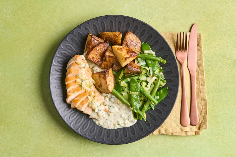 Serve up this posh chicken dinner and wait for the compliments to roll in! Juicy chicken breasts are slathered in a sublime sauce of onion, garlic, parsley and creamy Greek-style yogurt, crispy roast potatoes tossed with peppy horseradish and a side of sautéed leek, green beans and mangetout.