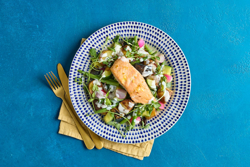 Put the zing into spring with this stunning salmon supper! Baby potatoes and onions are roasted with succulent salmon fillets – zinged up with lemon zest – and served with green beens, courgette and radish. A kick of horseradish in the lemony sauce and a sprinkle of pea shoots seal the deal.