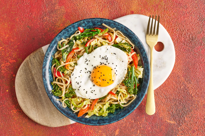 Slurpy noodles with a fried egg finale is the fix your cravings ordered – and it’s delivered fast! Simply sizzle long-stem broccoli, savoy cabbage, spring onions, red pepper and rice noodles with chilli flakes, ginger, garlic and soy. Finish with a squeeze of lime and a sprinkling of nigella seeds for those sunny side up eggs.