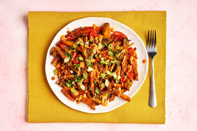 This scrumptious pile-on is unfussy, unapologetic… and unreal! What it lacks in airs and graces, it more than makes up for in punchy flavour. Potato and carrot chips are tossed with gochujang, then tumbled with sautéed onions, chestnut mushrooms and kimchi, plus juicy tomatoes, coriander and chilli. Drizzle on spiced yogurt, scatter spring onions and dig in.